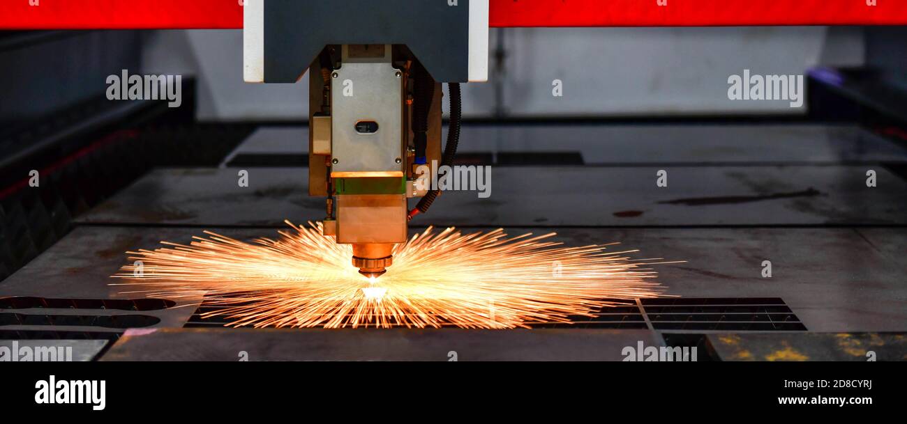 Laser cut head machine while cutting the sheet metal with the sparking light in factory Stock Photo