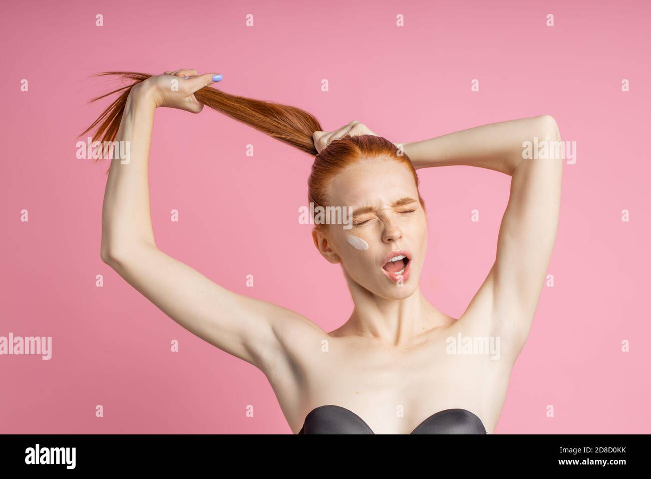 Redhead woman with strong healthy hair. Happy cheerful girl pulling