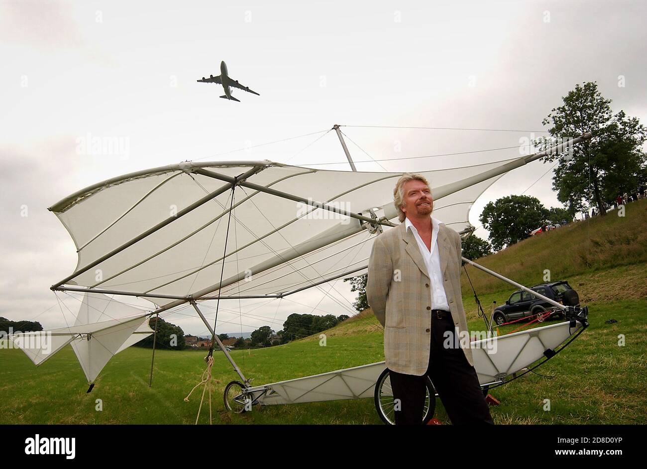 Richard Branson next to a replica of Sir George Cayley's glider, with a Virgin Atlantic Boeing 747 (G-VAST) flying overhead, before he recreates Cayle Stock Photo