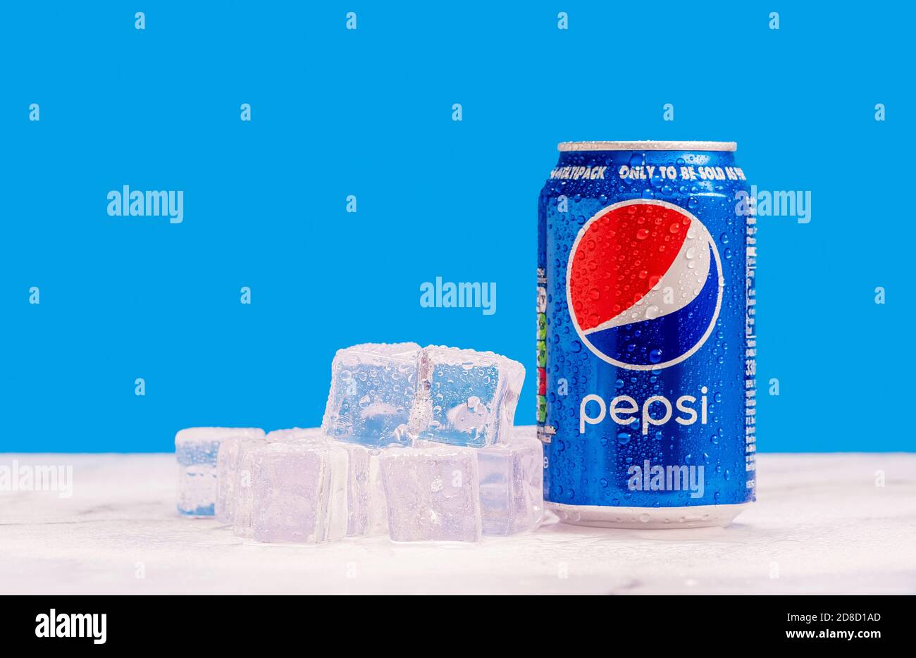 London, United Kingdom - October 29 2020:  Ice cold can of Pepsi and a pile of frozen ice cubes on blue background Stock Photo