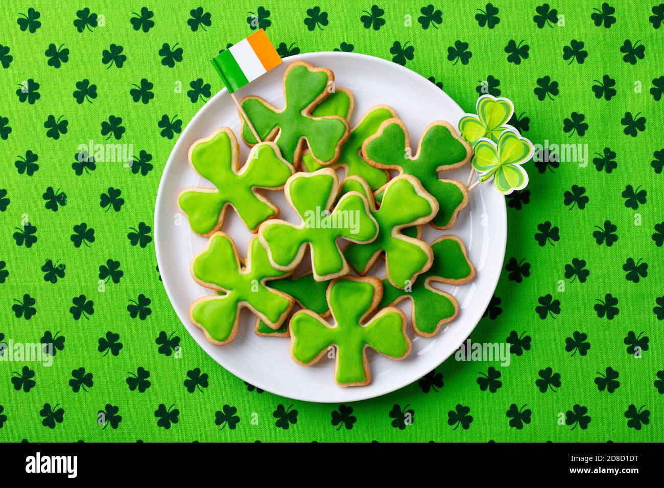 Shamrock cookies with Irish flag, St. Patrick's Day dessert. Green textile background. Top view. Stock Photo