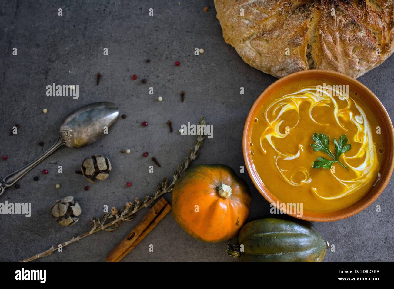 Pumpkin soup with fresh baked bread and silver spoon on gray table. Top view photo of vegan meal. Healthy eating concept. Stock Photo
