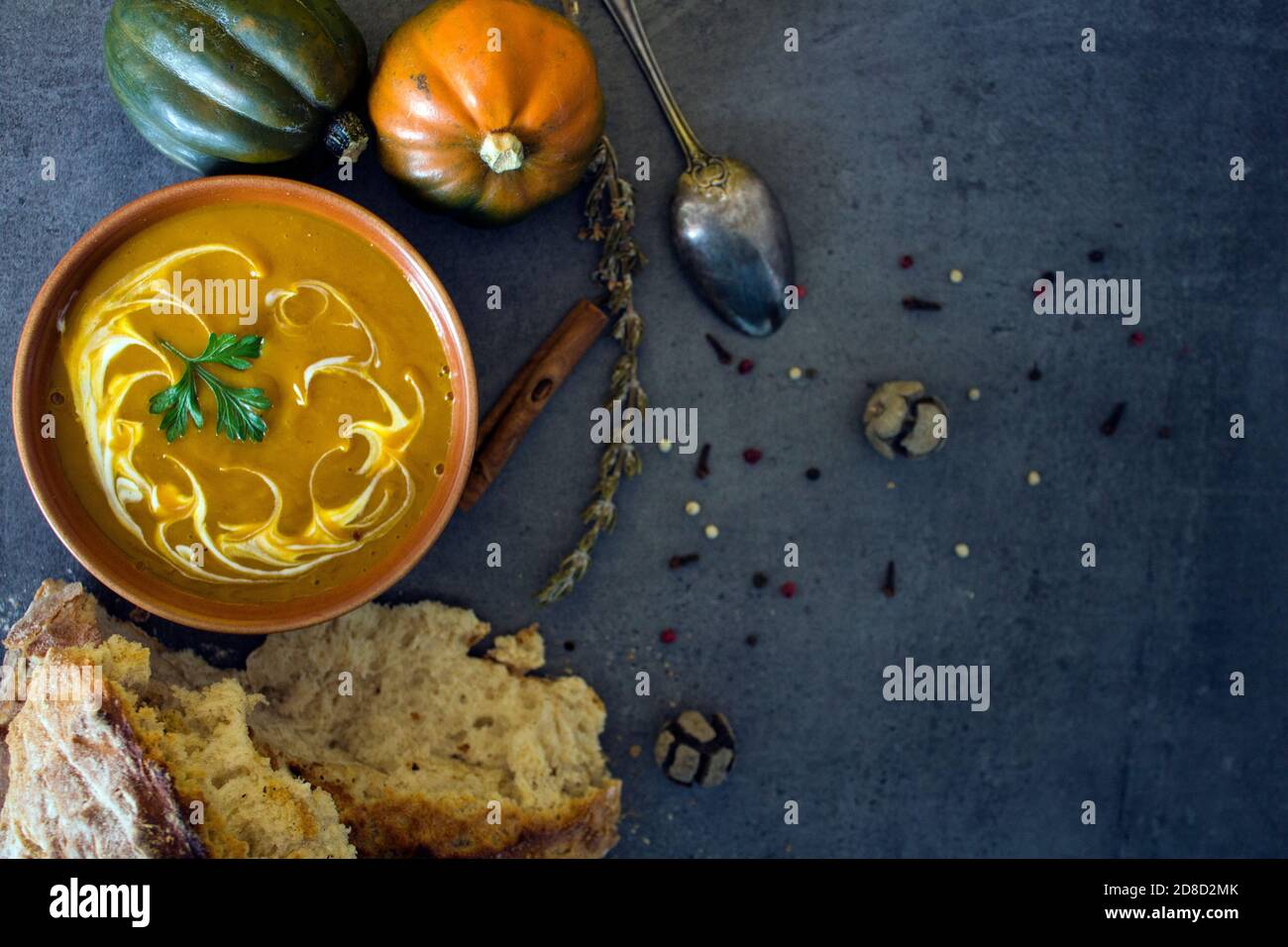 Pumpkin soup with fresh baked bread and silver spoon on gray table. Top view photo of vegan meal. Healthy eating concept. Stock Photo