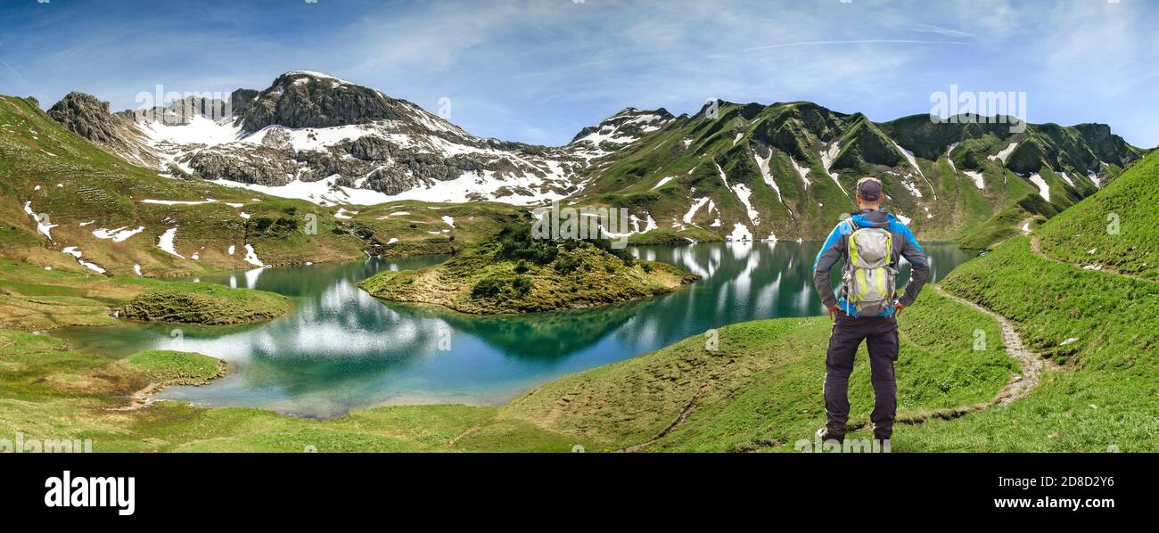 Hiking Man standing at remote lake up high in the alpine mountains. Alps, Bavaria, Schrecksee. Stock Photo