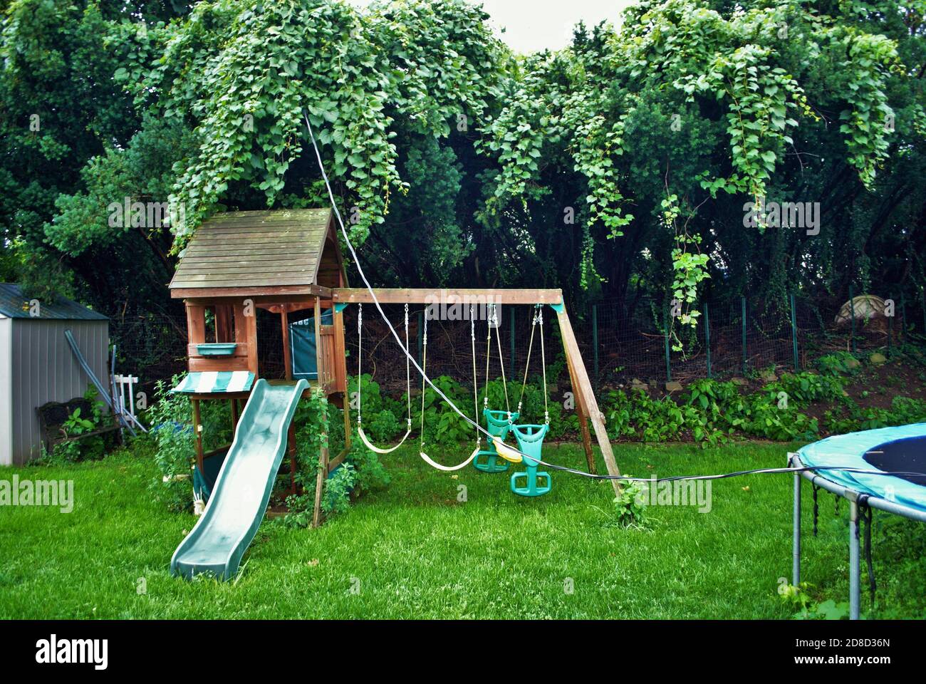 Dangerous live downed power line draped across trampoline and backyard playground Stock Photo