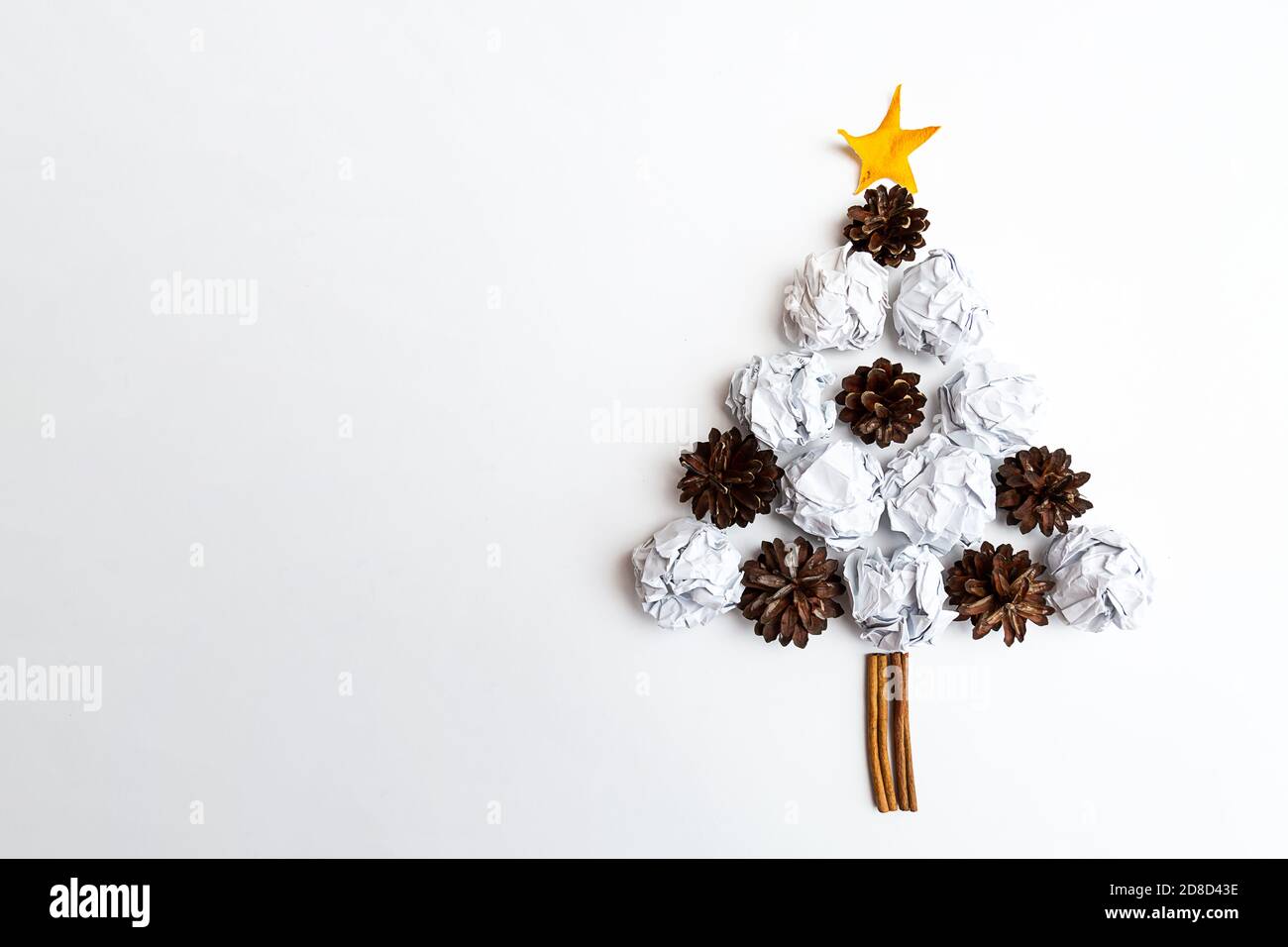 The Christmas tree is made of white paper crumpled into balls and pine cones on a white background. Christmas and New Year concept Stock Photo