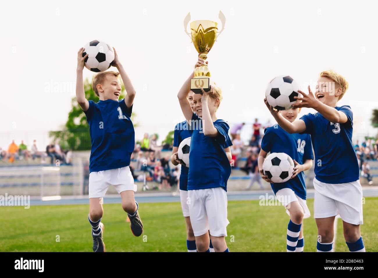 Happy boys in elementary school sports team celebrating soccer succes in tournament final game. Kids winning football game. Happy children sports team Stock Photo