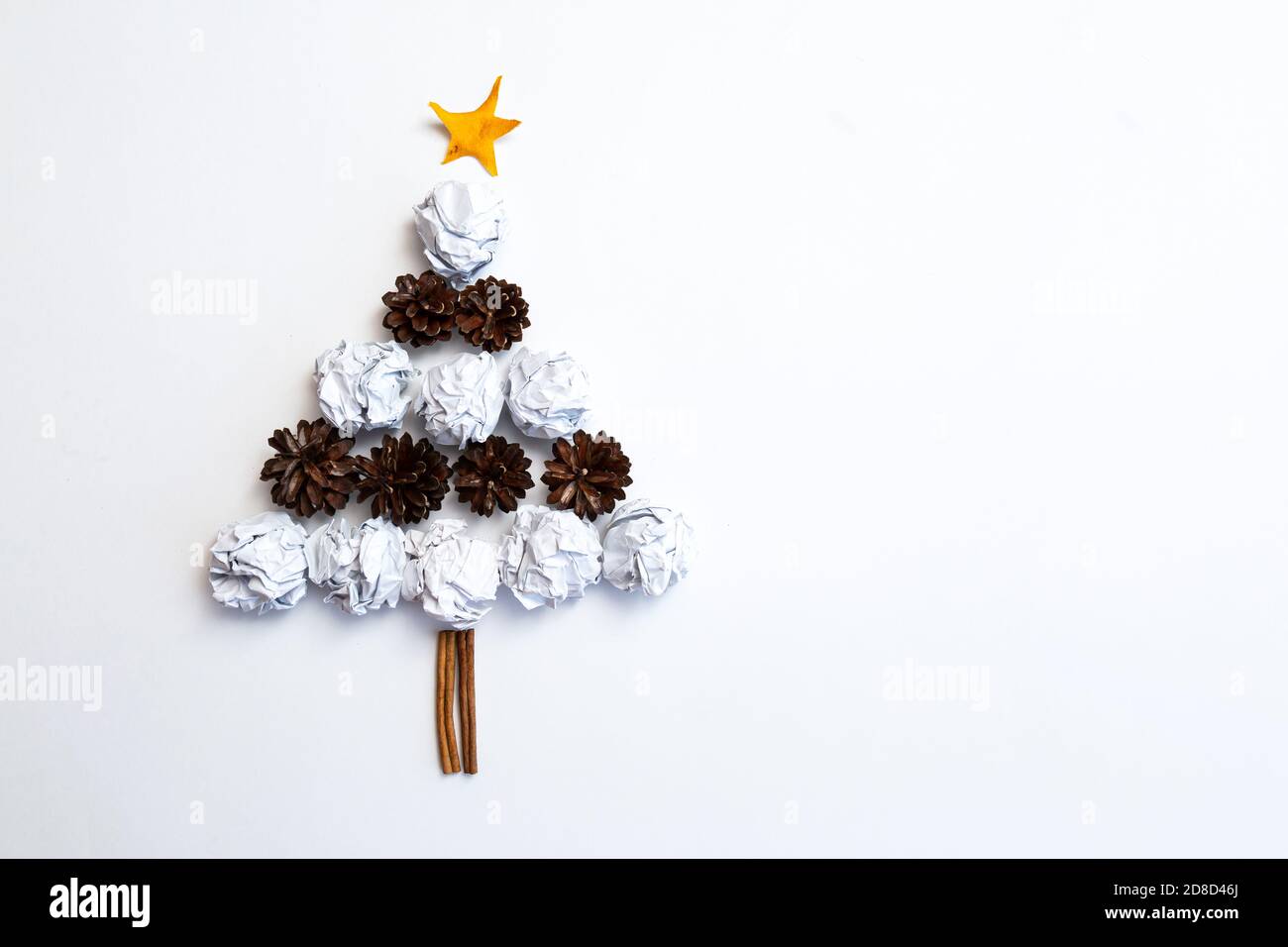 The Christmas tree is made of white paper crumpled into balls and pine cones on a white background. Christmas and New Year concept Stock Photo