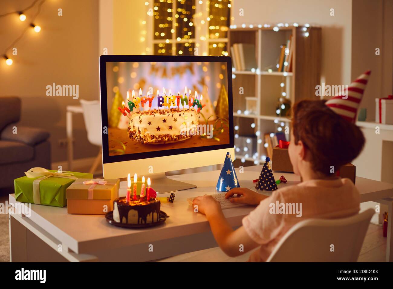 Little boy having online birthday party and looking at beautiful cake on computer screen Stock Photo