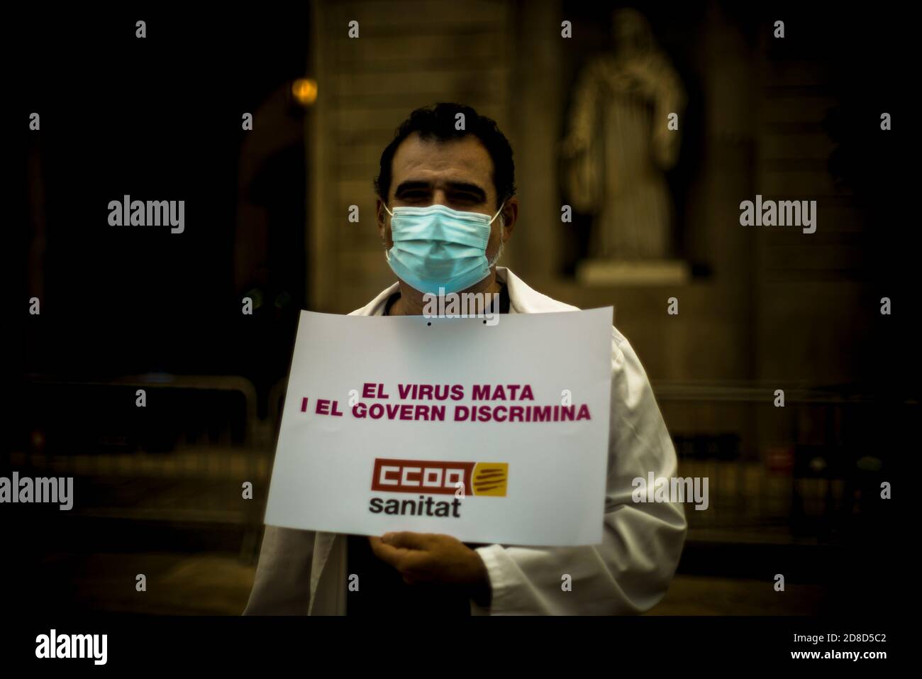 Barcelona, Spain. 29th Oct, 2020. A member of the public healthcare sector holds a placard reading 'the virus kills - the government discriminates' during a protest for higher salaries and safer work conditions in front of Barcelona's City Hall at the beginning of the second coronavirus wave Credit: Matthias Oesterle/Alamy Live News Stock Photo