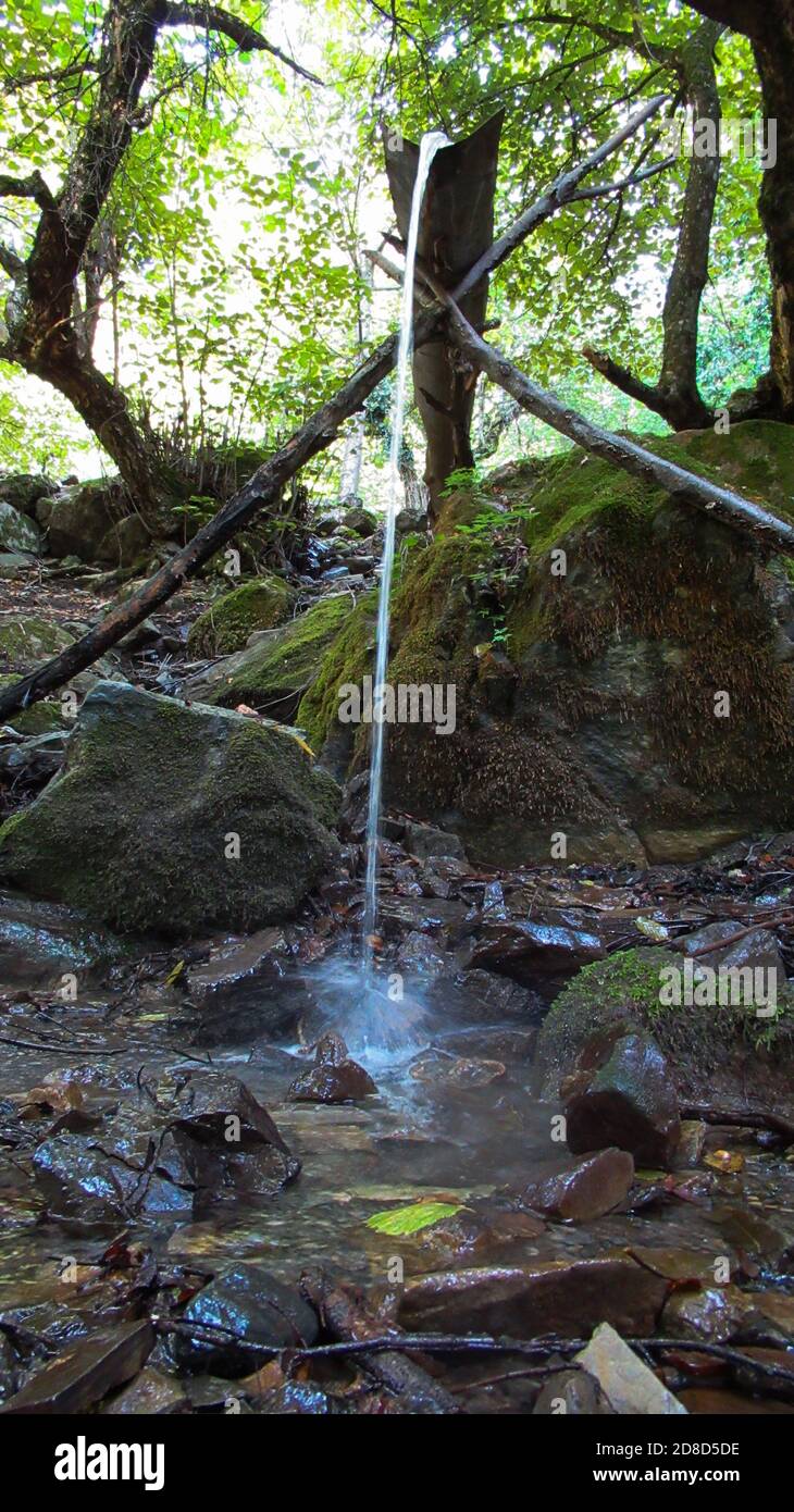 Water coming from the top of the mountain falling down on to rocks ...