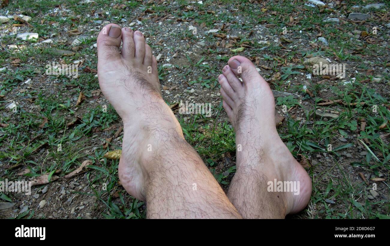 Only lower legs showing of a man lying in a green field, cross-legged and  barefoot resting in the grass Stock Photo - Alamy