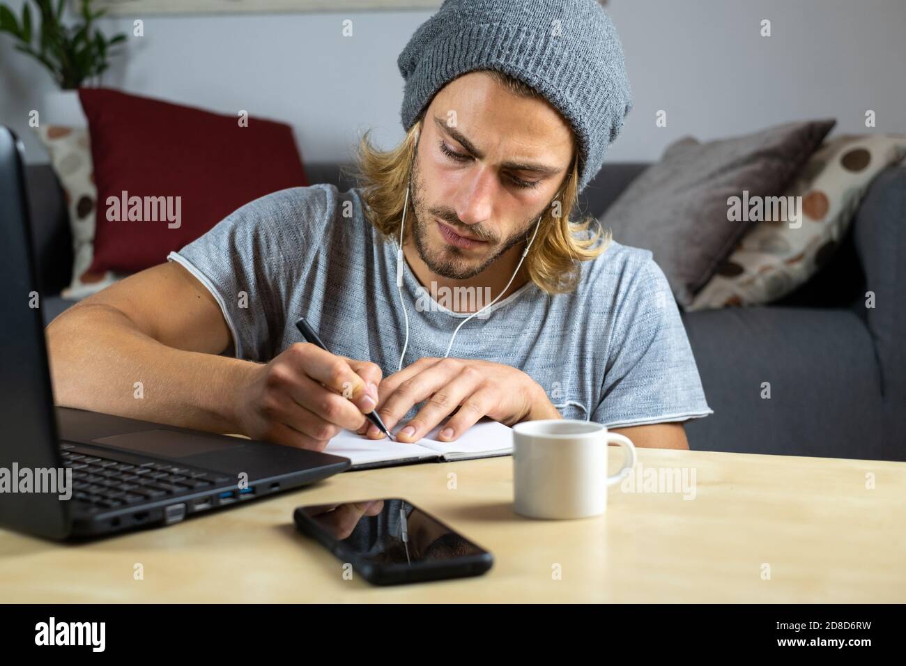 Handsome young caucasian man using computer working at home and learning online and writing notes Stock Photo