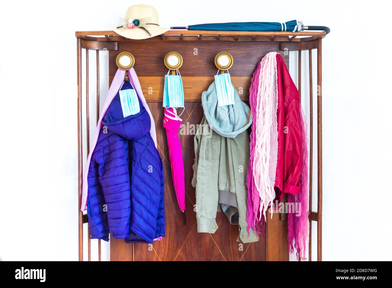 winer jackets and umbrellas hanging on the clothes hanger with protective face masks..coats and hat hanging on the wall.concept about new normal life Stock Photo
