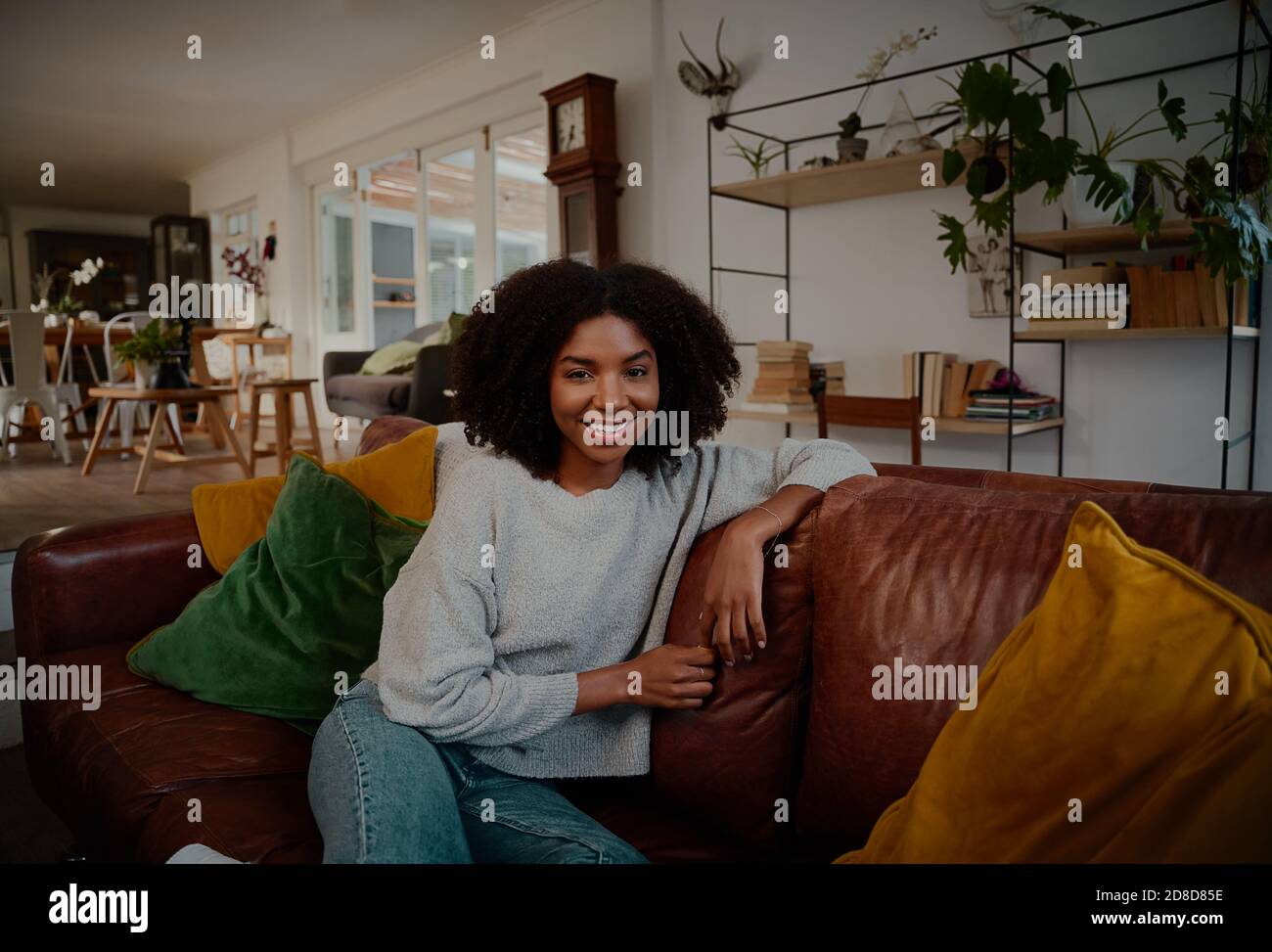 Happy young african woman sitting on sofa at home during covid19