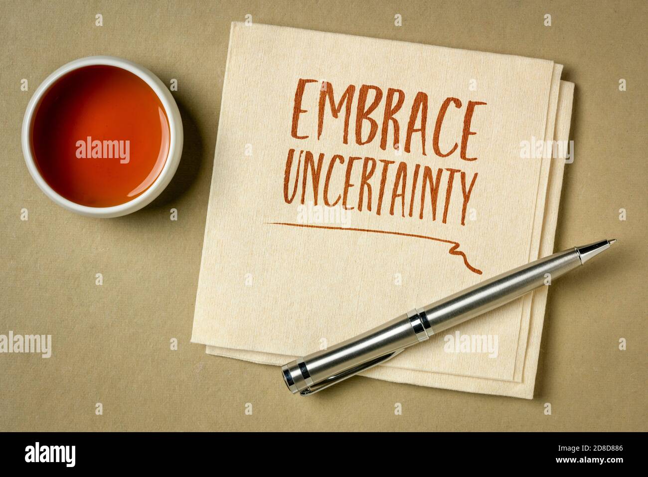 embrace uncertainty motivational note - handwriting on a napkin with a cup of tea, unknown future, change, risk and chance concept Stock Photo