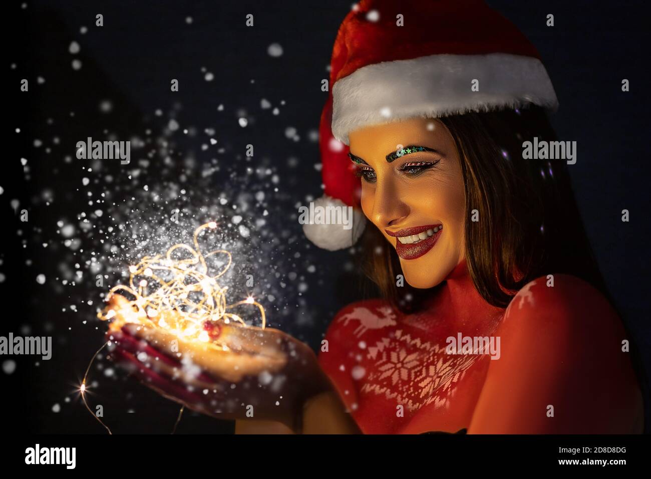 A beautiful brunette girl with art make-up, wearing a Santa Claus hat ...