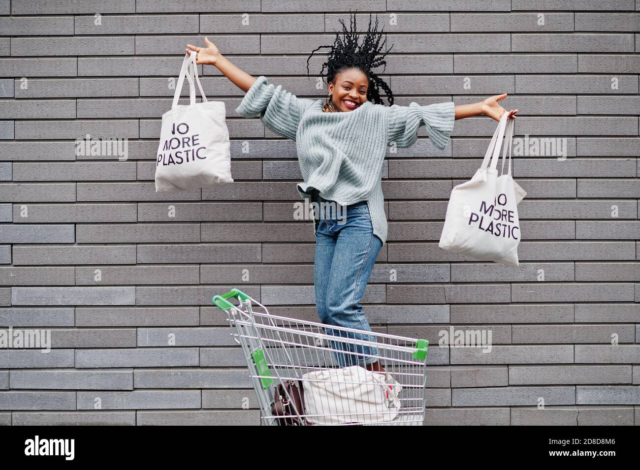 No more plastic. African woman with shopping cart trolley and eco bags