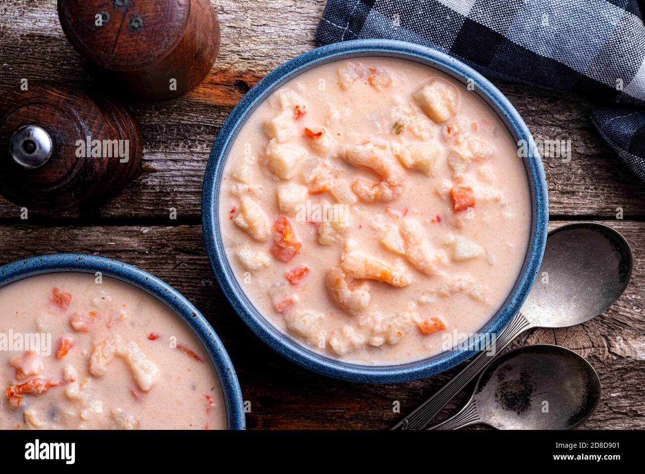 A bowl of delicious seafood chowder with lobster, shrimp, scallops, potato, carrots and cream. Stock Photo
