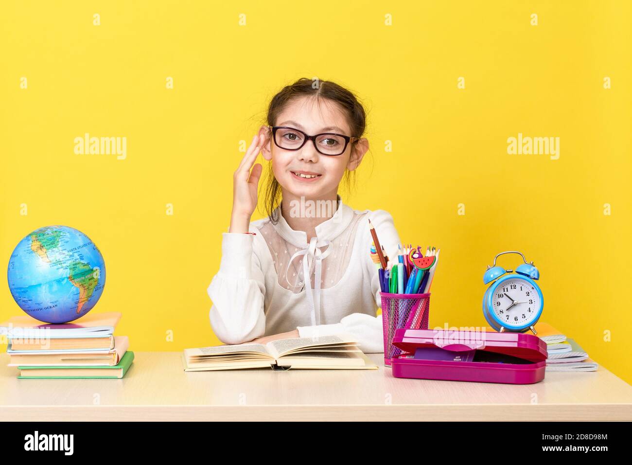 The schoolgirl sits at the desk and raises her hand for an answer. Back ...