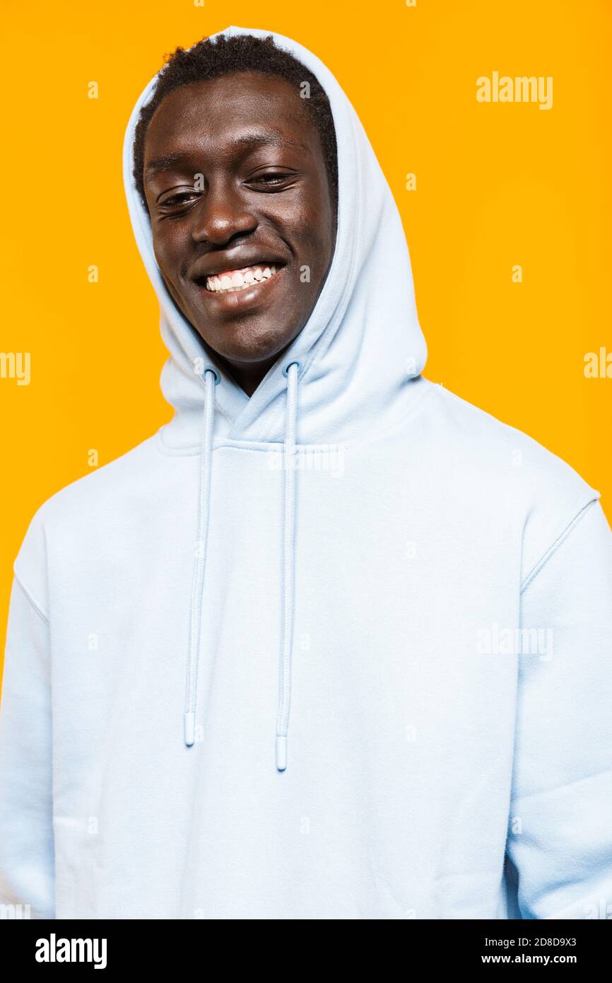 Image of pleased african american guy in streetwear hoodie standing and ...