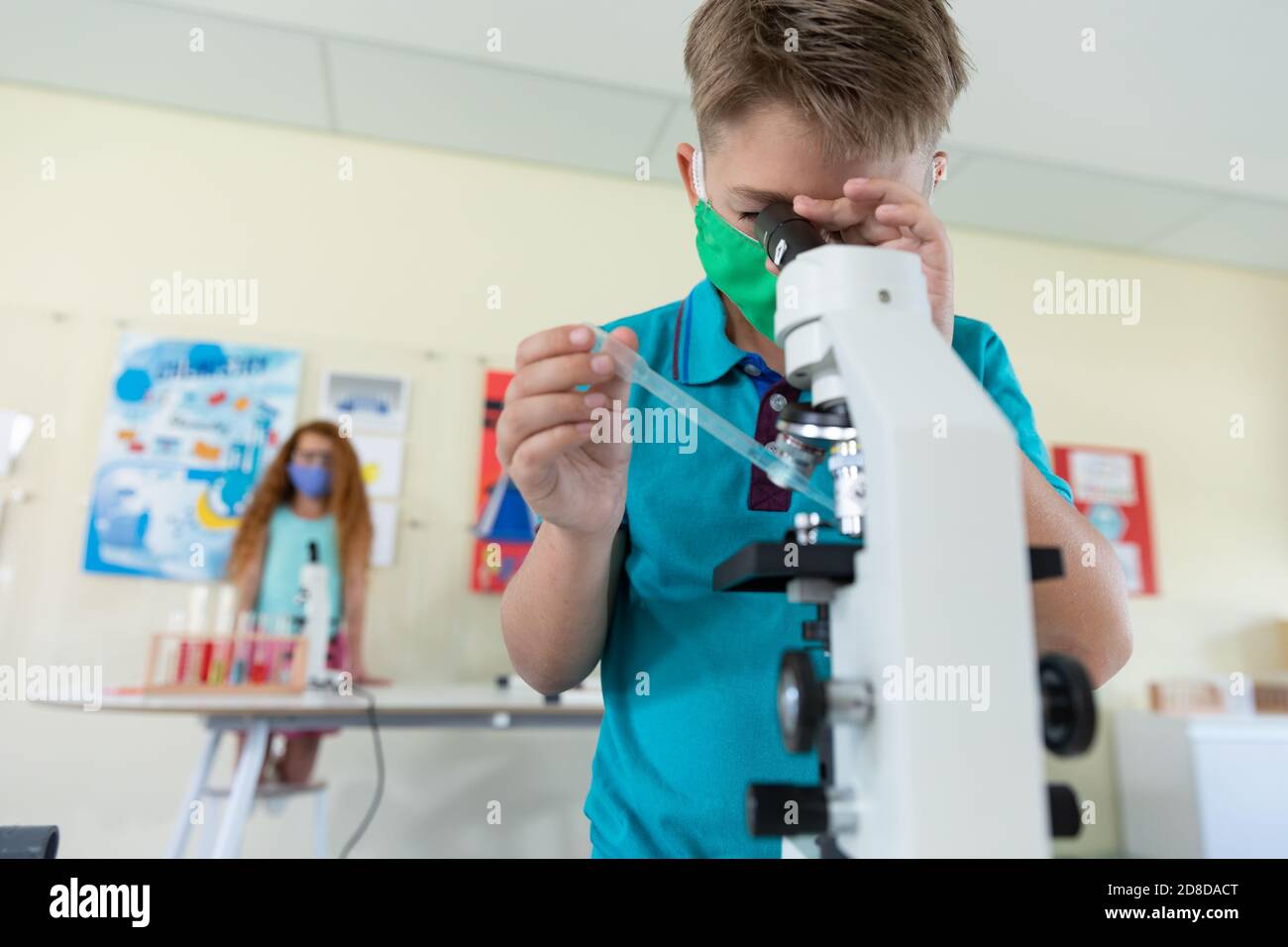 Boy wearing face mask and protective glasses holding pipette using