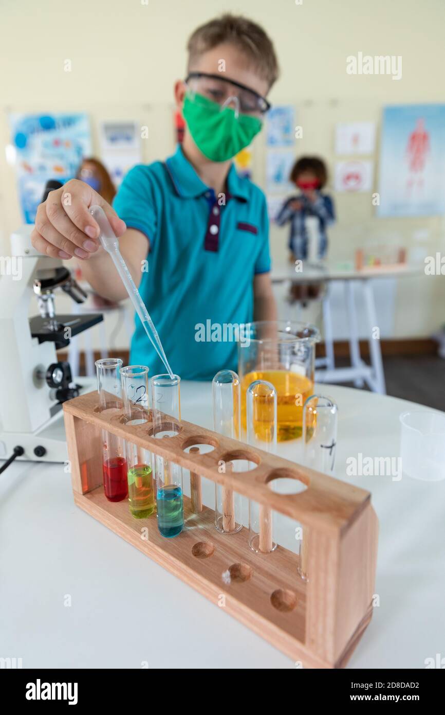 Boy wearing face mask and protective glasses using pipette and test