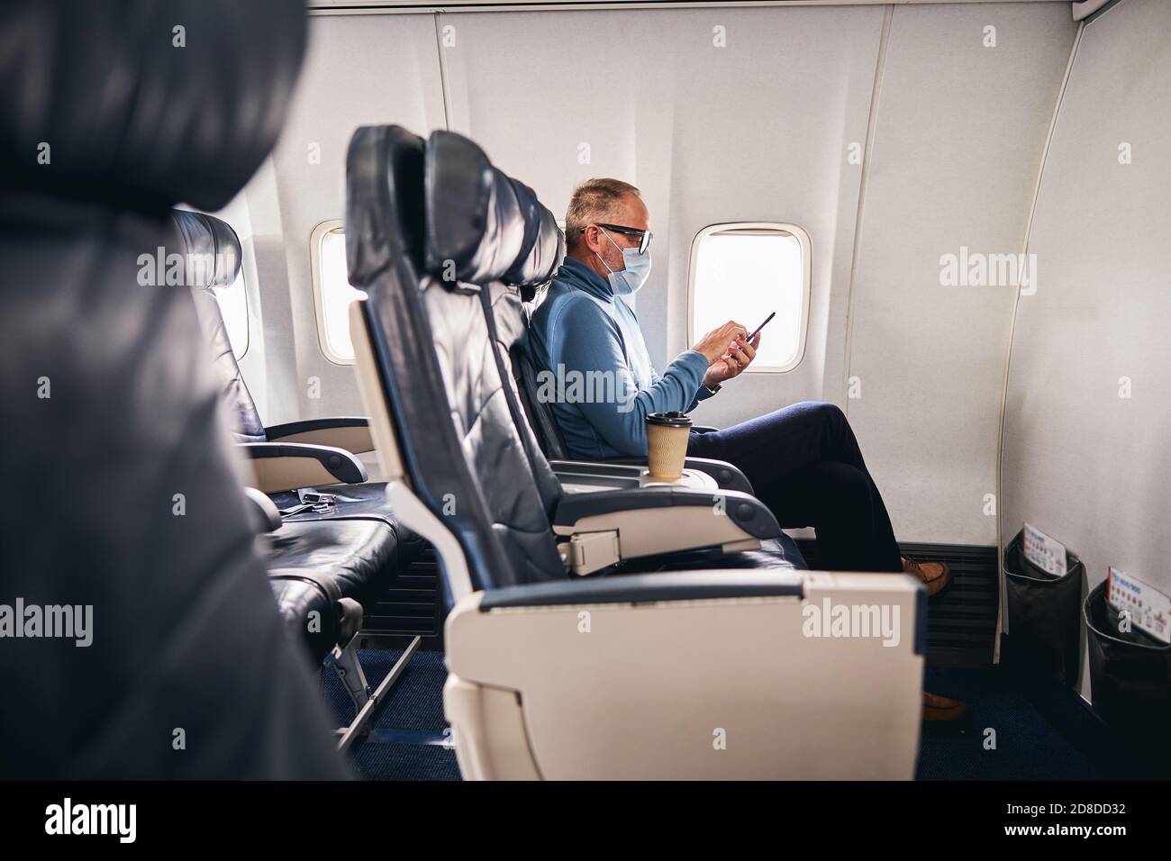 Concentrated businessman using his cellphone during the flight Stock Photo