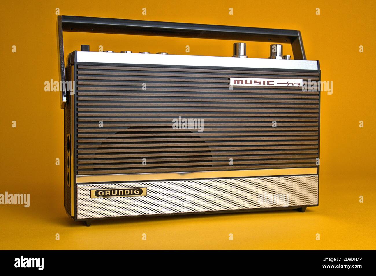 Schleswig, Deutschland. 28th Oct, 2020. An old portable radio made by Grundig, type Music-Boy 209, which was built and sold from 1969 to 1970. Photo against a vintage 1970s style background. The radio has a dynamic, permanent oval speaker behind a panel with a wooden look, an output of 1.5 watts and has a handle. | usage worldwide Credit: dpa/Alamy Live News Stock Photo
