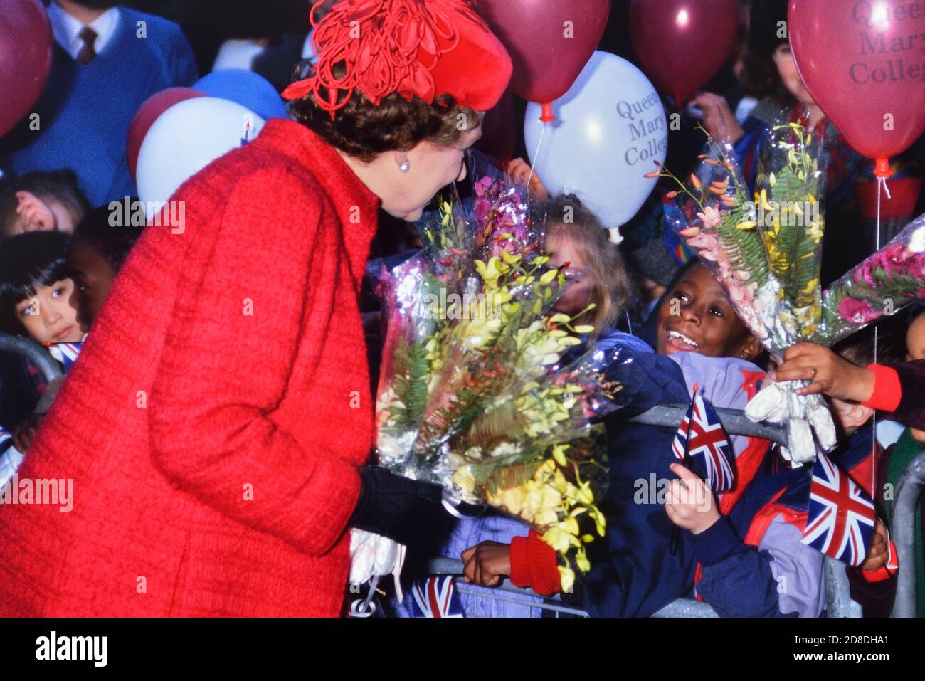 HRH Queen Elizabeth II surrounded by happy and excited children at the