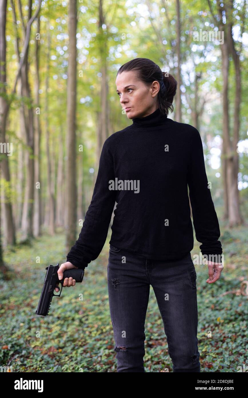 tough woman holding a hand gun in the woods. Stock Photo