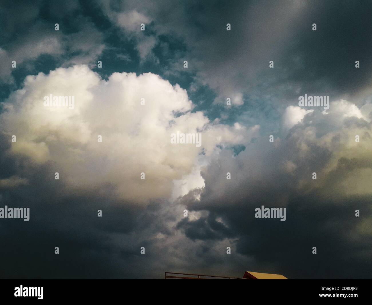 Dramatic massive dark clouds under blue sky settle for heavy rainfall in day time Stock Photo