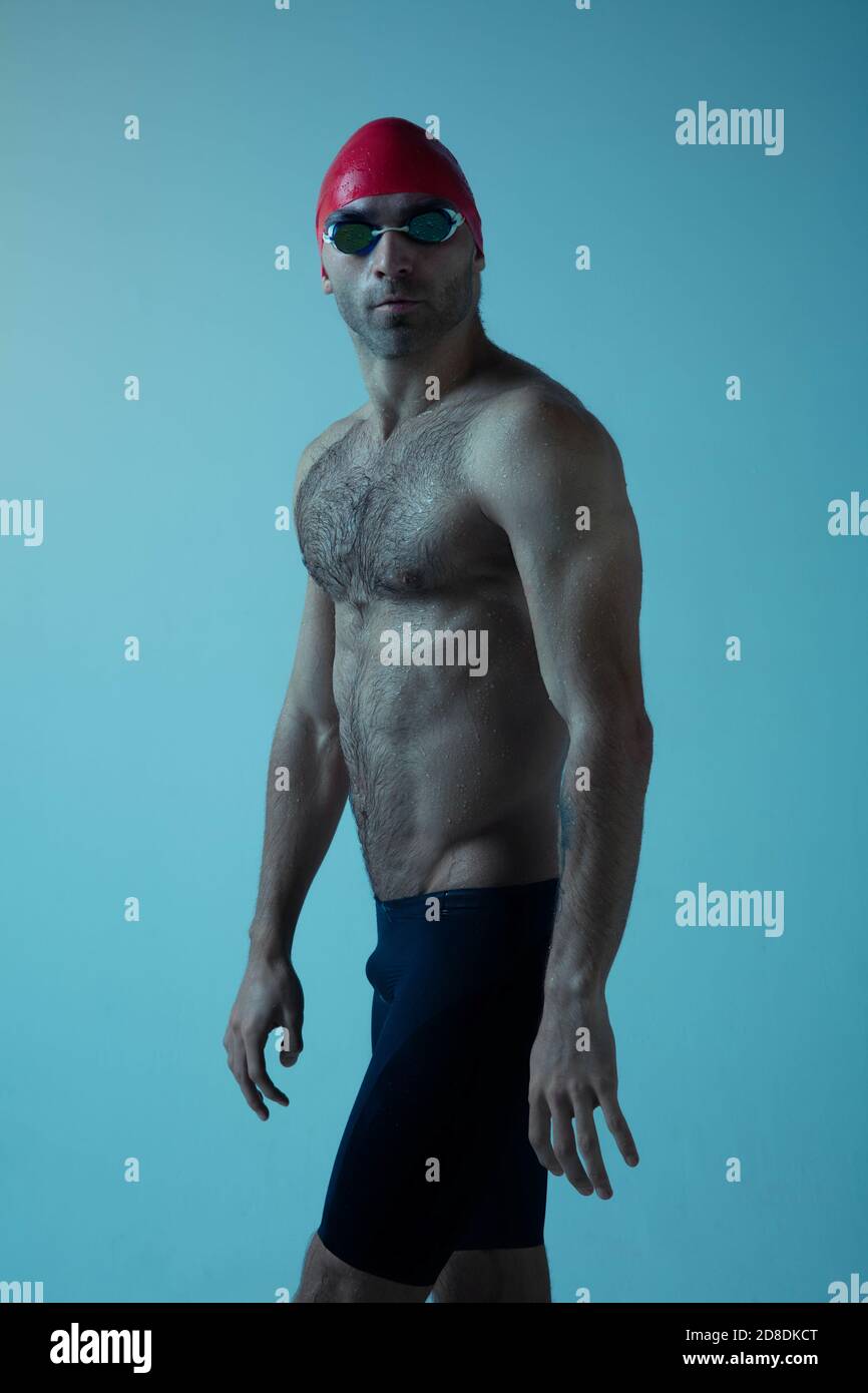 Professional caucasian male swimmer with hat and goggles practicing and