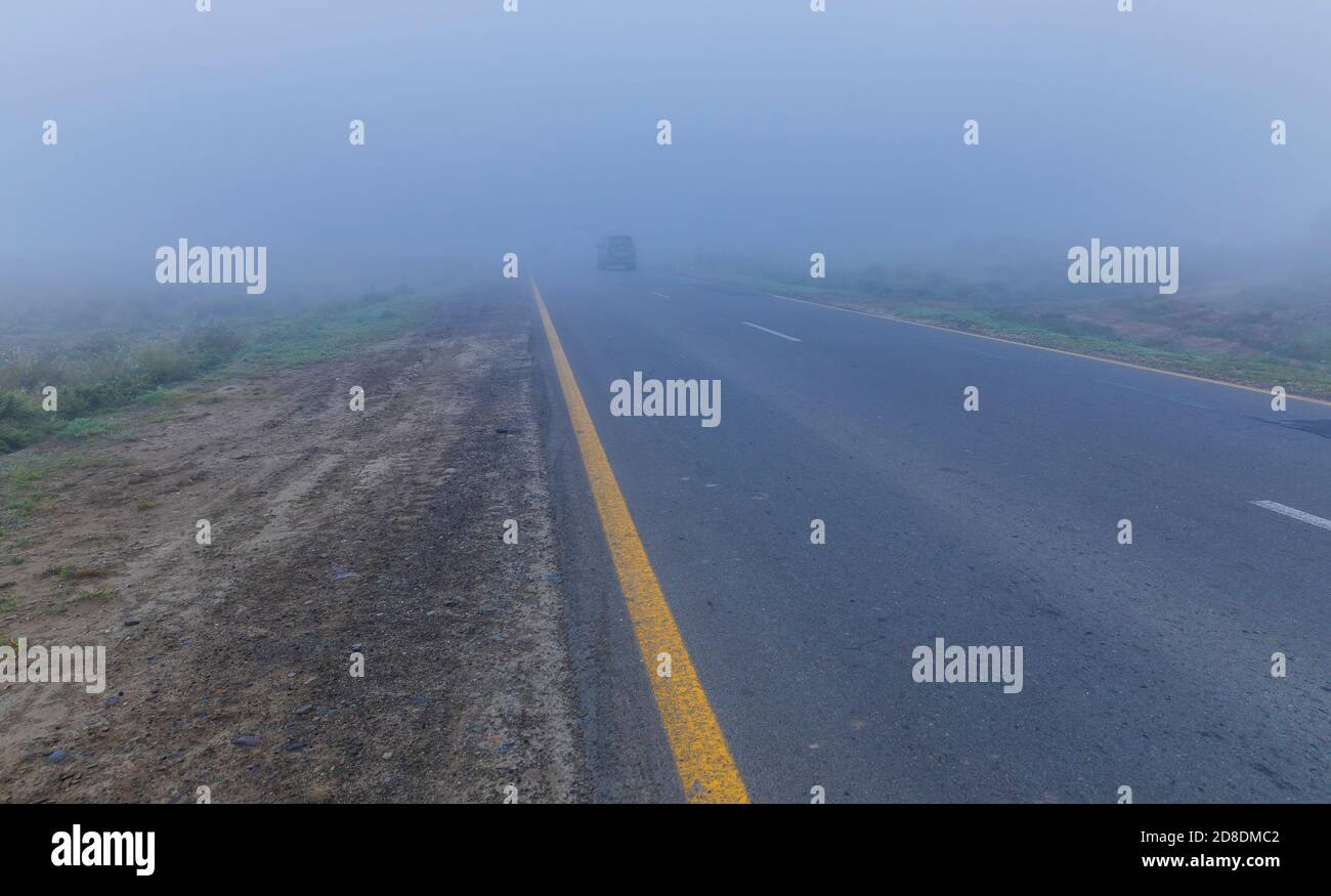 Asphalt road leaving in autumn fog Stock Photo - Alamy