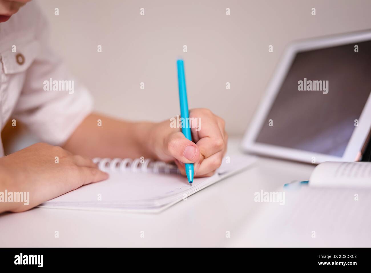 Close up of child's hand making notes in the writing pad lying on the ...