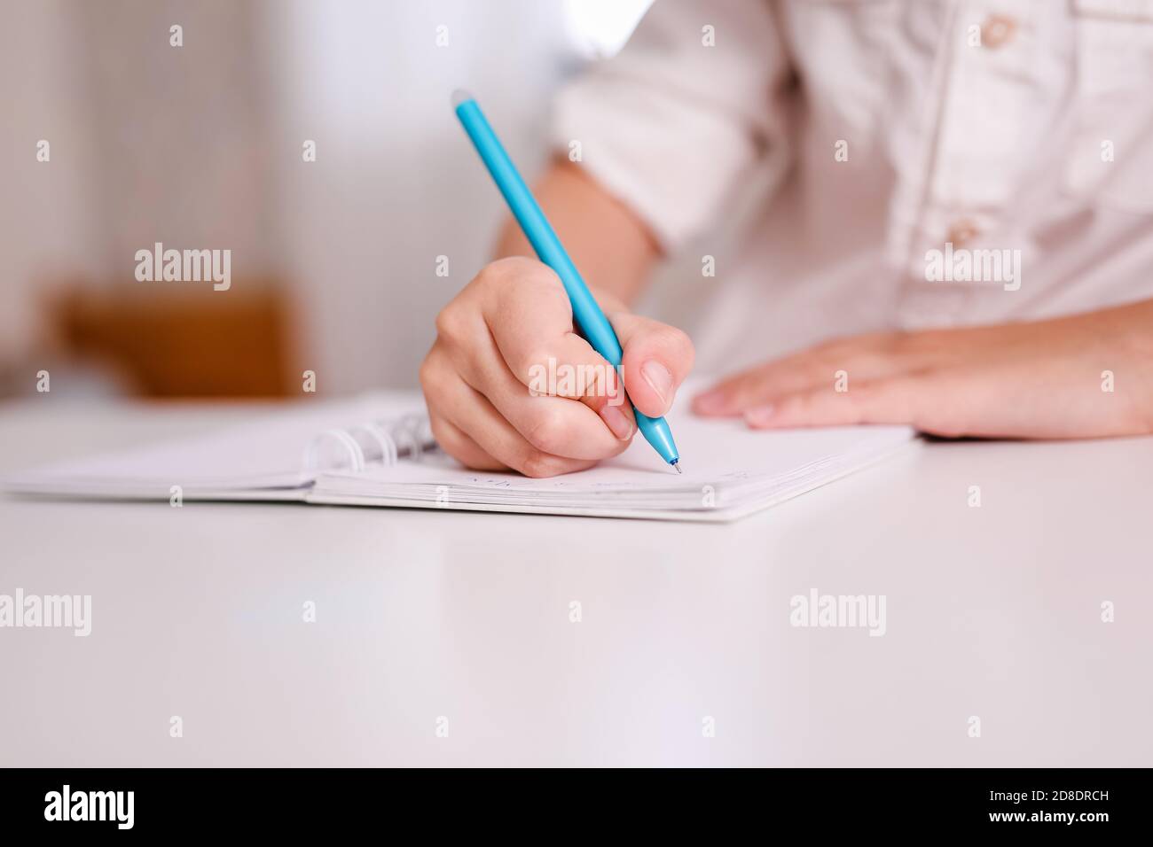 Close up of child's hand making notes in the writing pad lying on the ...