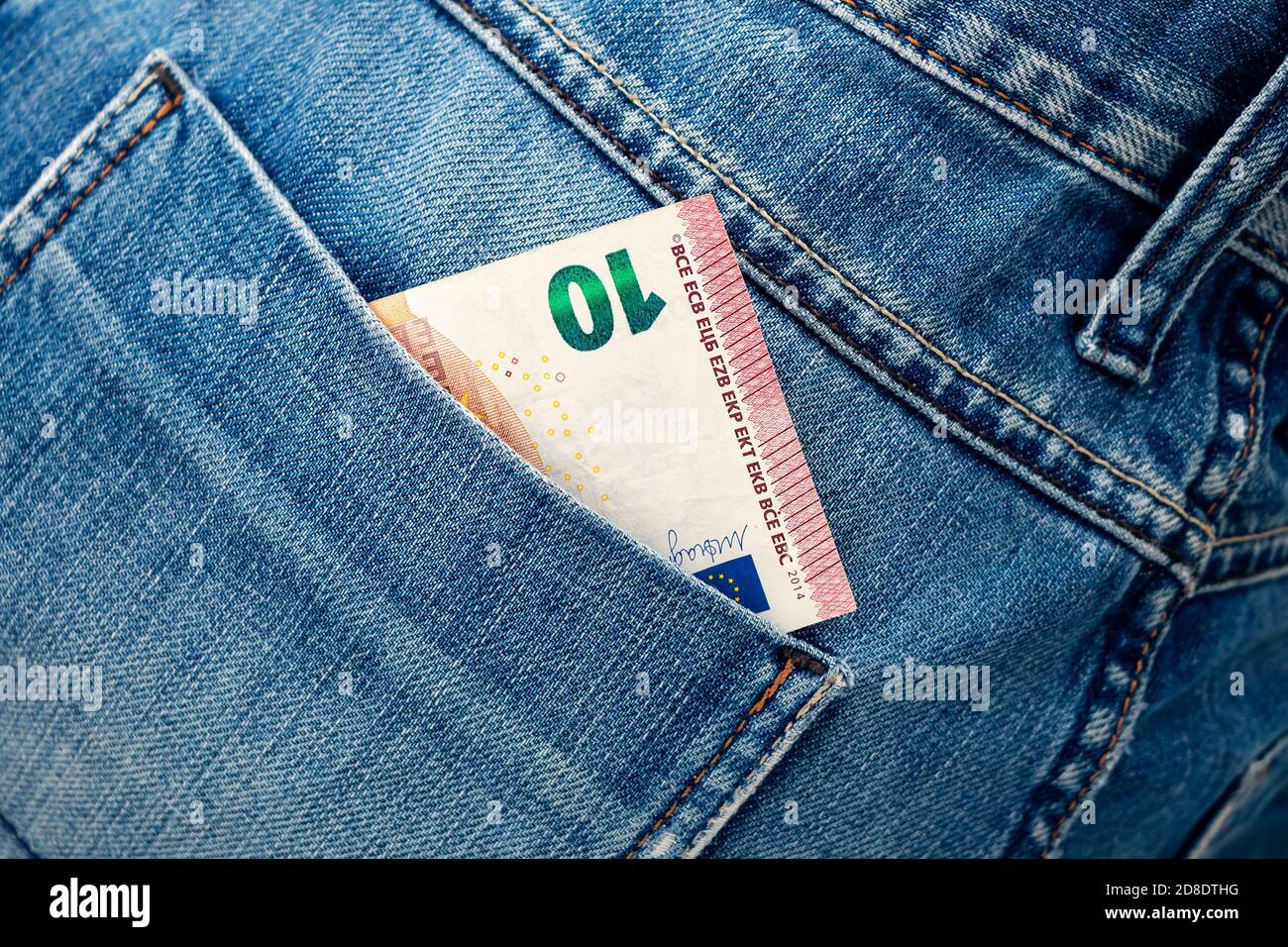 Euro bill in the back pocket of jeans. Ten Euro in a denim pocket. Close-up Stock Photo