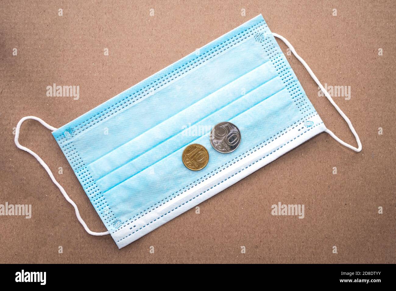 Blue medical mask and sixty Kazakhstani tenge. Medical mask and 60 KZT on a textured background. Price cap concept. Flat lay Stock Photo