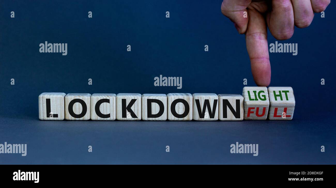 Symbol for a second lockdown. Hand turns cubes and changes the expression 'lockdown full' to 'lockdown light'. Copy space. Beautiful white background. Stock Photo