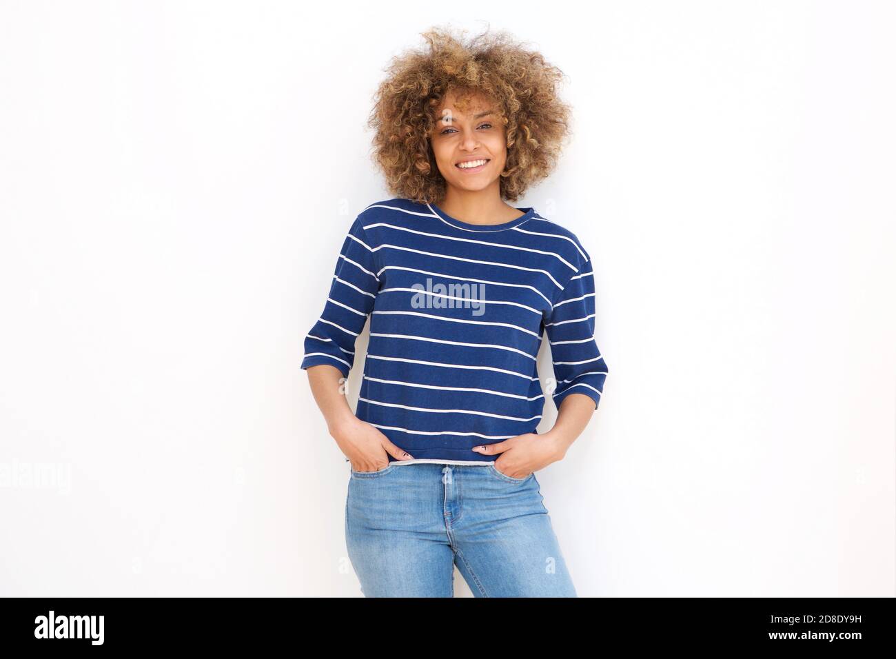 Portrait of smiling black young woman leaning against white wall Stock ...