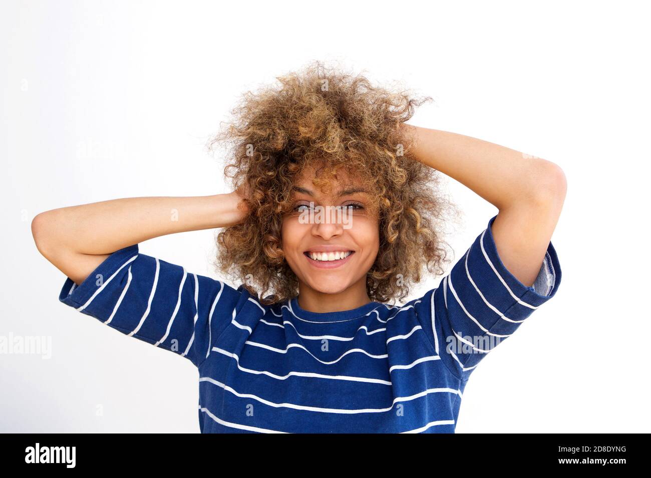 Close up portrait of beautiful african american young woman smiling with hands in hair against white wall Stock Photo