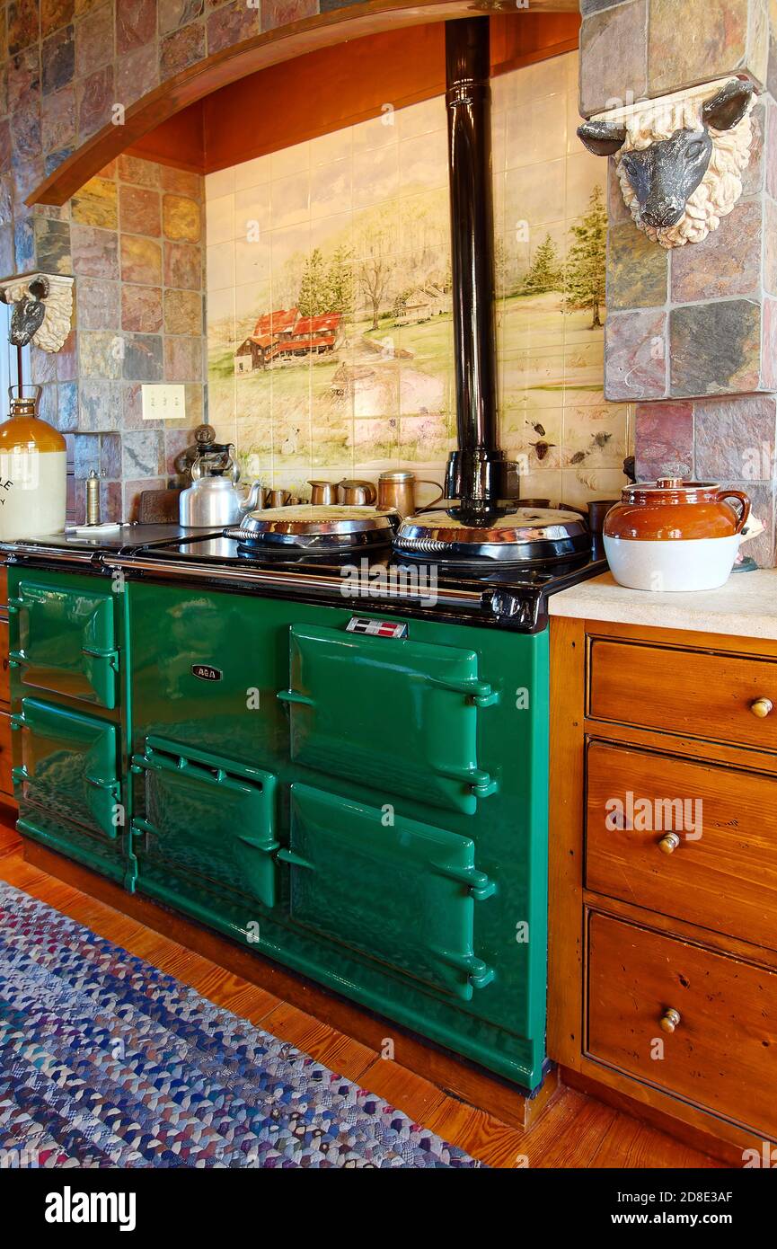 Aga range, covered burners, multiple ovens; cooking appliance, dark green; tile scene; stone wall; country kitchen; house, room, Pennsylvania, PA, PR Stock Photo