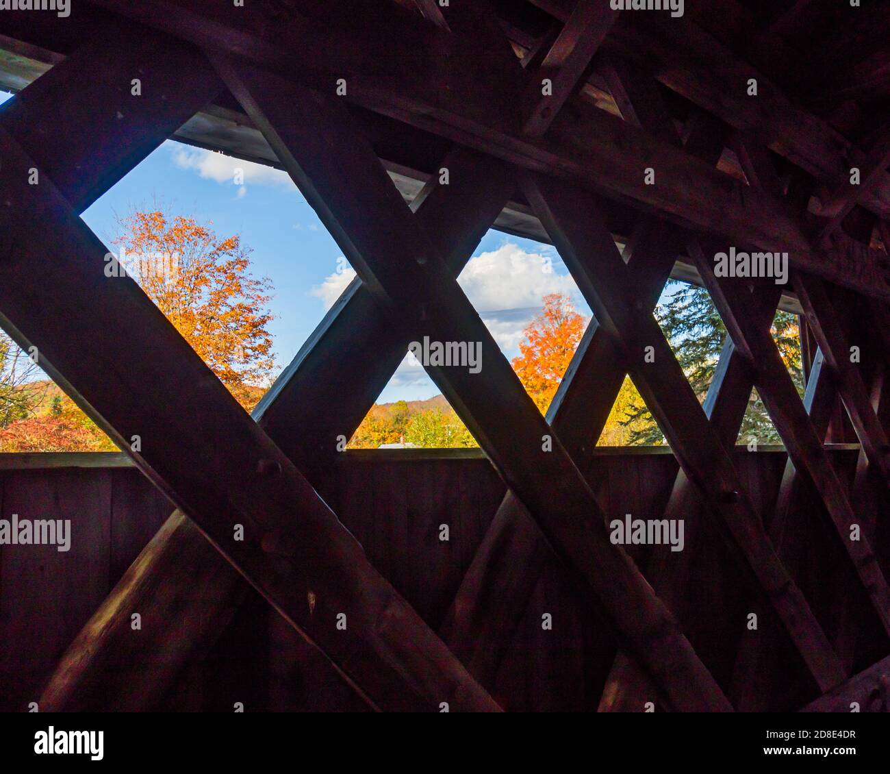 looking though the lattice wooden architecture of covered bridge at fall foliage Stock Photo