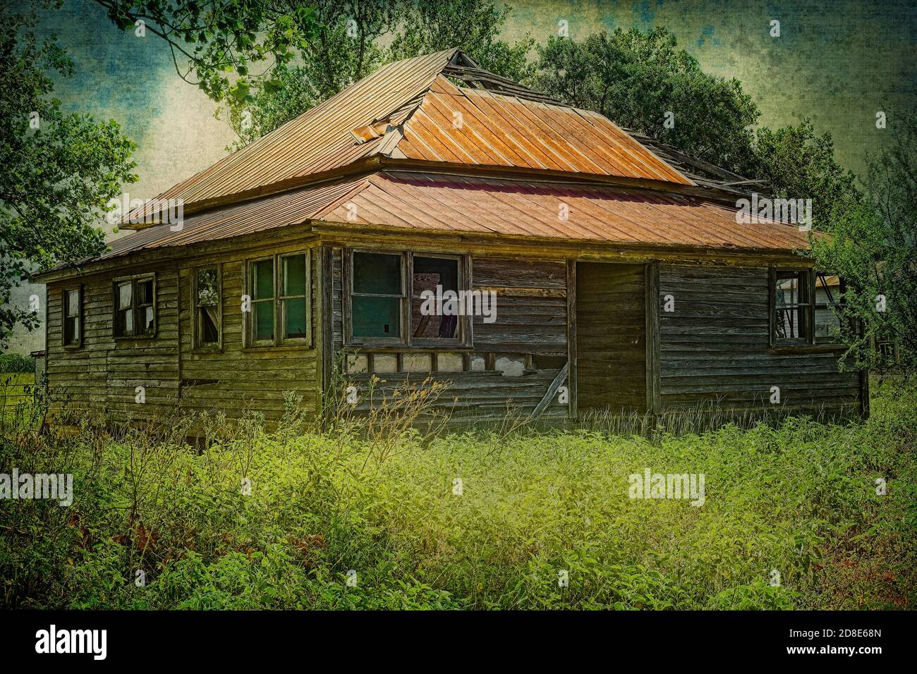 Abandoned farm house with rusted metal roof surrounded by trees and