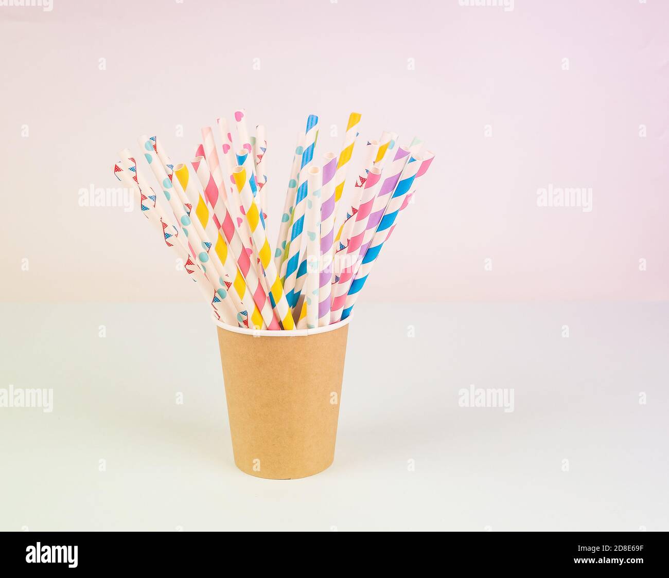 Kraft paper cup with colorful straws on blue background Stock Photo - Alamy