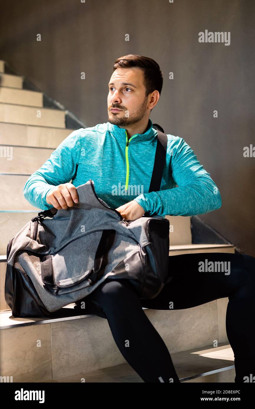 Portrait of young fit man athlete with bag after workout in gym Stock Photo