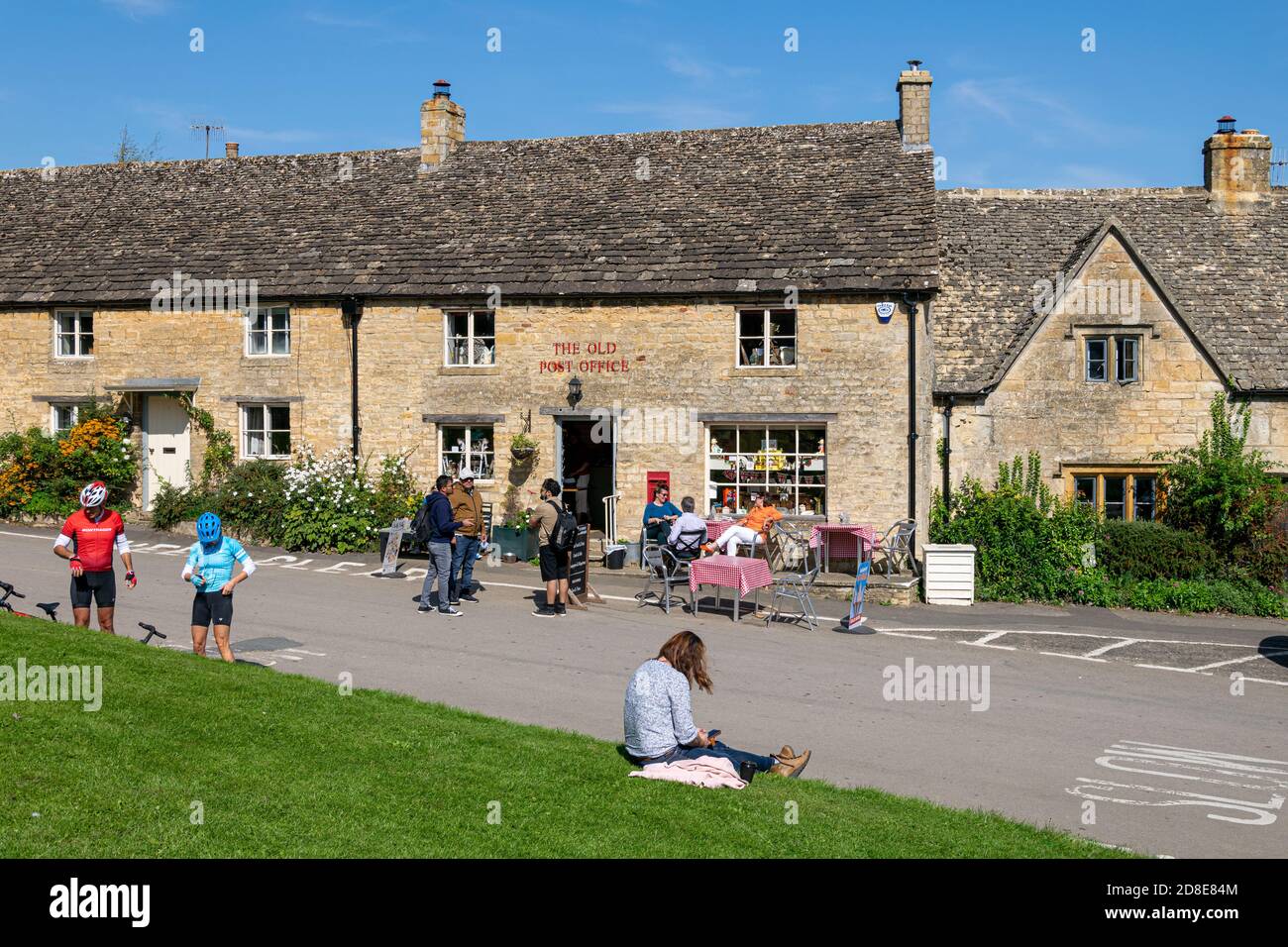 Cyclists and walkers outside the Old Post Office on the green in the Cotswolds, Guiting Power, England Stock Photo