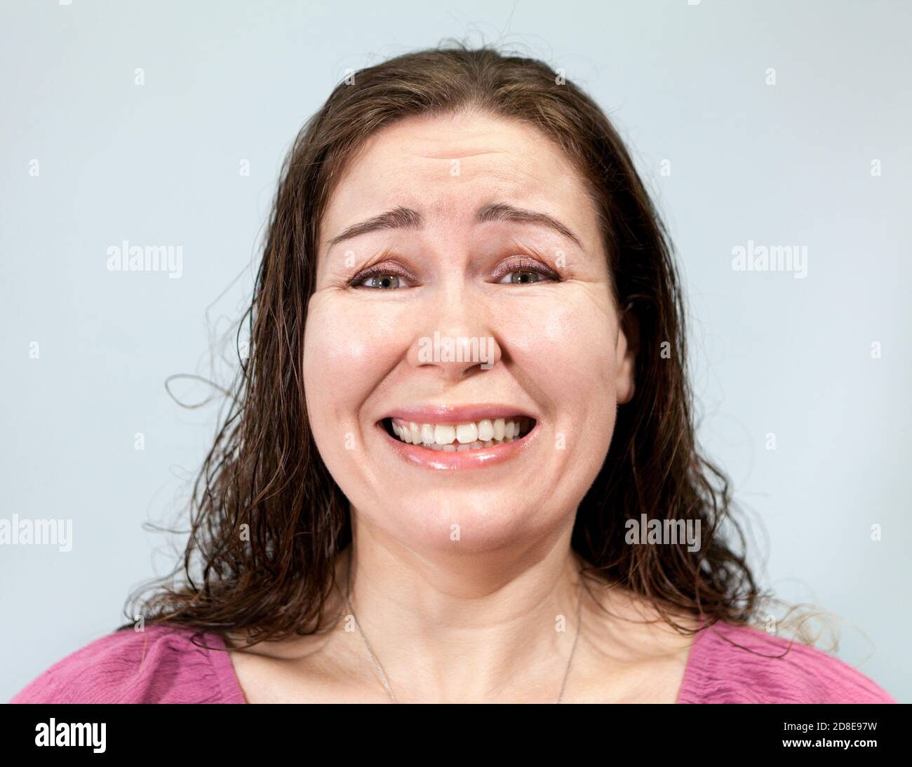 Uncertainty and embarrassment on the face of an adult woman, portrait on grey background, emotions series Stock Photo