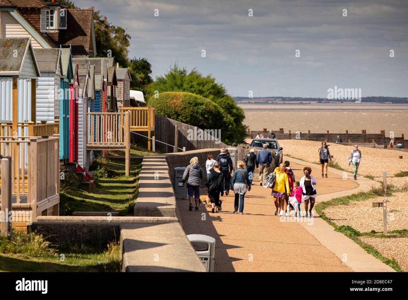 UK, Kent, Whitstable, Tankerton beach, walkers on promenade below beach huts Stock Photo