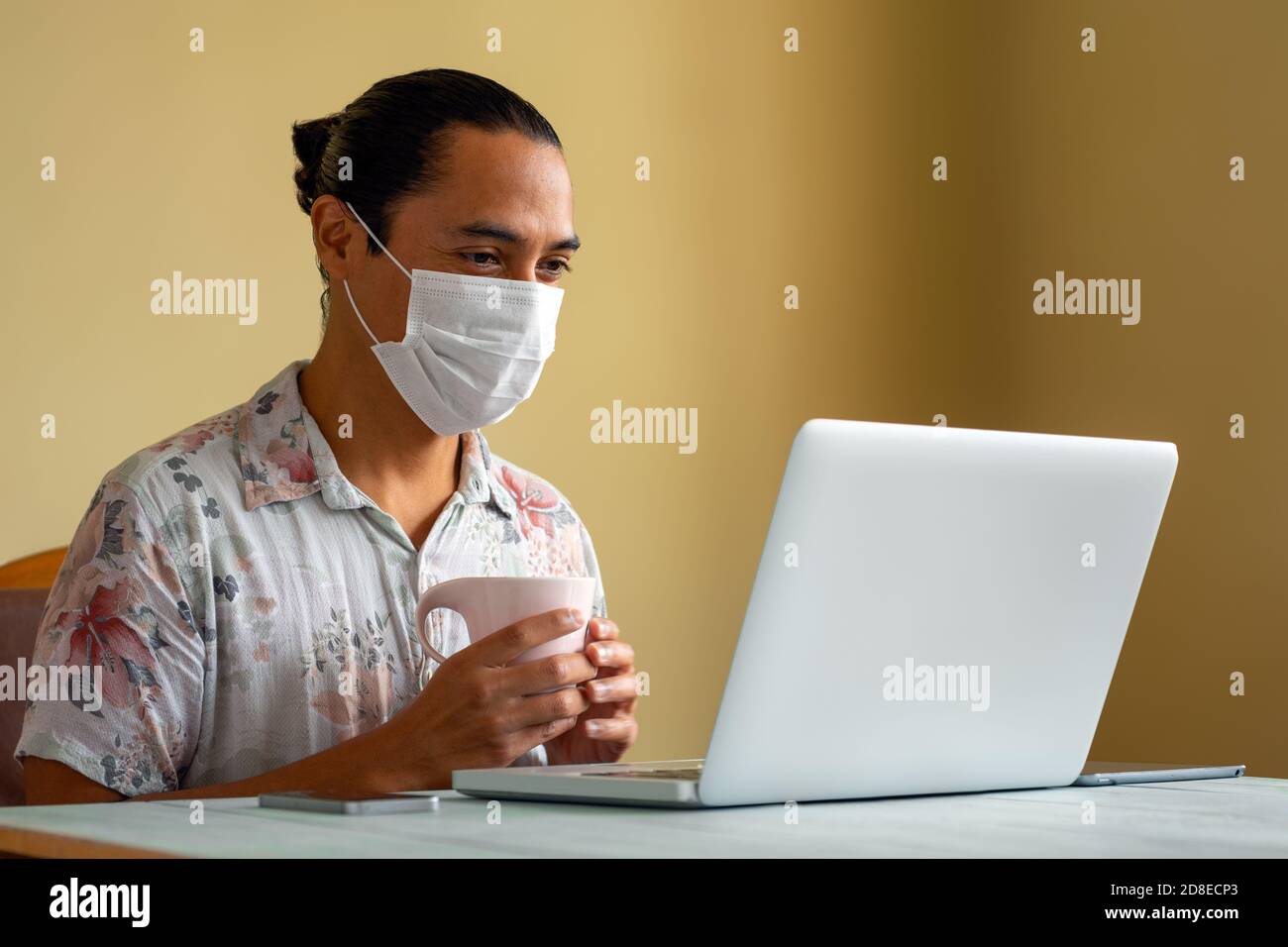 Young latin man with medical mask works relaxed at home. Copy space. Coronavirus concept. Stock Photo